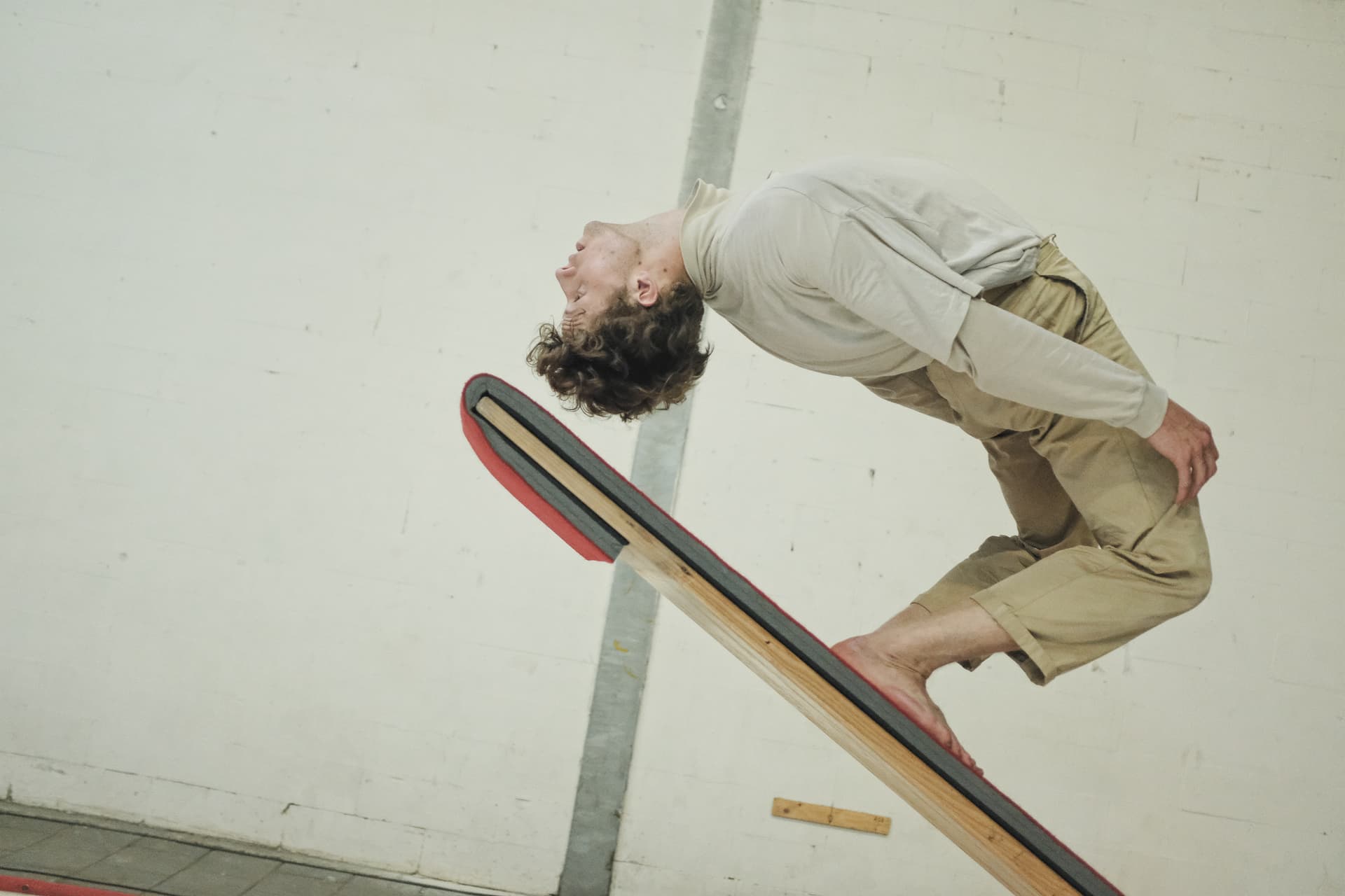 Eine Person steht mit nach hinten gebogenen Rücken auf einer steilen Wippe.